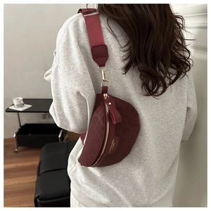 Détail du sac croissant bordeaux avec fermetures dorées et large bandoulière tissée rouge
