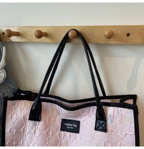 Detail of pink quilted tote bag featuring wave embroidery and fashion brand label