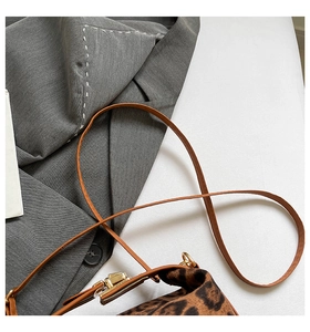 Détail du sac léopard avec fermoir doré et bandoulière en cuir sur fond neutre
