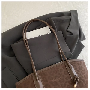 Close-up of leopard print tote bag with embossed text detail on a stylish grey blazer