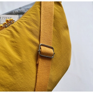 Detail of ginger nylon crossbody bag with wide shoulder strap and silver metal buckle