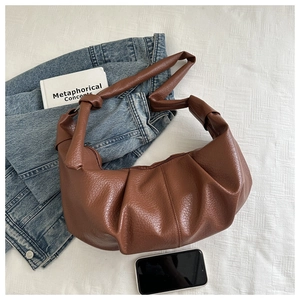 Detail view of brown pleated hobo bag with litchi texture and stylish knot strap