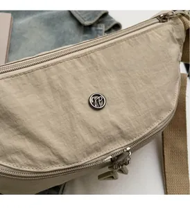 Dettaglio borsa a tracolla in nylon kaki con logo in metallo e finitura in tessuto lucido