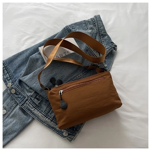 Close-up of brown nylon crossbody bag featuring a cute bear zipper pull and wide strap