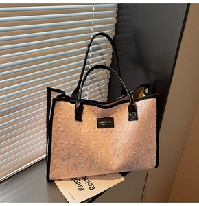 Detailed view of pink quilted tote bag with colorful wave embroidery and black leather straps