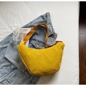 Detailed view of the bright yellow nylon half-moon crossbody bag in a lifestyle setting