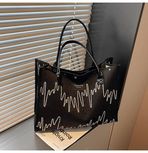 Detail of black tote bag featuring colorful wavy stitching and a New York fashion patch