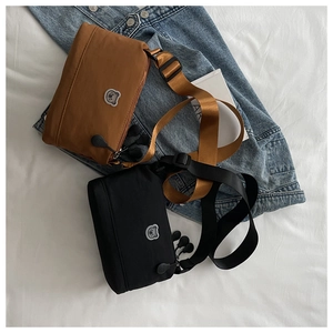 Detail of small nylon crossbody bags in black and brown with cute bear patches