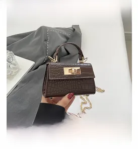 Detail view of dark brown faux crocodile leather mini bag with gold twist lock and chain