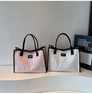 Detail of pink and white tote bags featuring rainbow embroidery and textured relief patterns