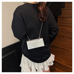 Close-up of a silver chain bag with mim logo worn by a model in a minimalist style