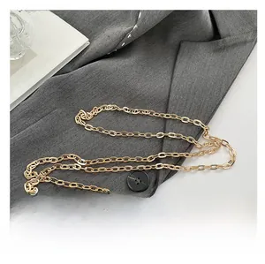 Close-up of polished golden oval link chain strap on a dark grey blazer background