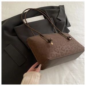 Detail of leopard print tote bag with knot strap and metallic gold hardware accents