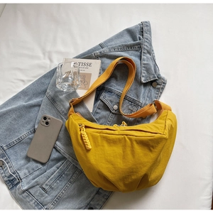 Detail view of yellow crescent nylon shoulder bag on blue denim jacket background