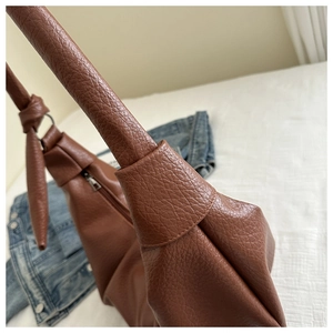 Close-up of brown pebbled faux leather shoulder bag with decorative knotted strap detail