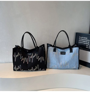 Detail of color-block quilted tote bags with wave embroidery and leather handles