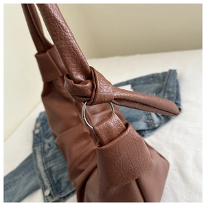Close-up of brown litchi grain leather bag strap with silver metal ring and knot detail