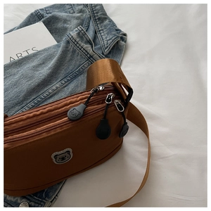 Detail of tan nylon crossbody bag with multi-layer zippers and cute bear pulls