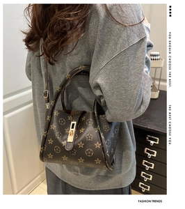 Detail of vintage brown tote bag featuring star pattern and golden metal twist lock