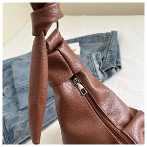 Detail of vintage brown PU leather shoulder bag featuring knot strap and silver zipper