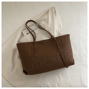 Close-up of leopard print tote bag placed on white fabric next to a beige blazer