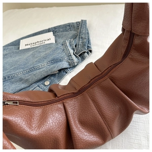 Detailed view of brown faux leather hobo bag with pleated texture and silver zipper
