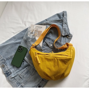 Detail of a bright yellow crescent nylon crossbody bag with an adjustable strap