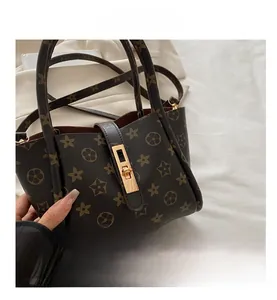 Detail of dark brown tote bag with floral pattern and golden square lock clasp closure