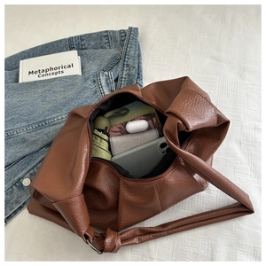 Detail of a brown pleated hobo bag showing large capacity for phone and umbrella