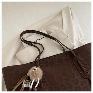 Detail of leopard print tote bag with brown faux fur charm and textured fabric finish