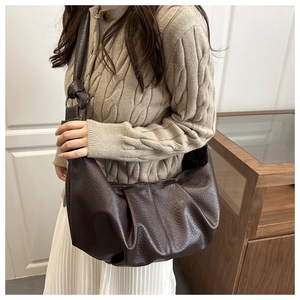 Detail view of the textured brown pleated crossbody bag showing leather grain and knot detail