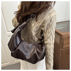 Detail of dark brown croissant bag with textured PU leather and stylish shoulder knot