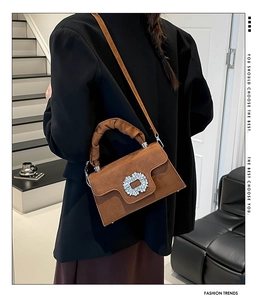 Detail of brown suede crossbody bag with rhinestone buckle and pleated handle