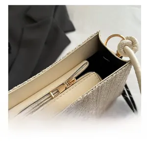 Detail showing smooth gold-tone zipper and beige woven texture on the interior bag