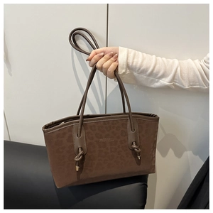 Detail of dark brown leopard embossed tote bag with unique knotted strap and brand logo