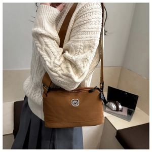Close-up of brown nylon crossbody bag featuring a cute cartoon bear patch detail
