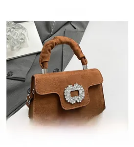 Detail of caramel brown suede handbag with large rhinestone buckle and pleated handle