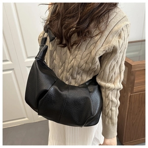 Detail of black pebbled leather dumpling bag with soft pleats and knotted shoulder strap