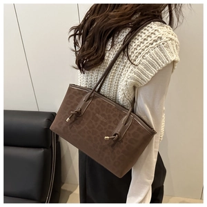 Detail of a brown leopard print tote bag with soft suede texture and knotted gold details