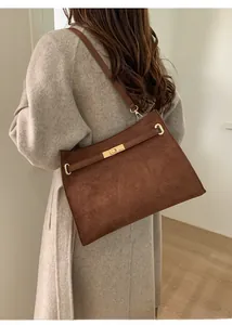 Detailansicht der dunkelbraunen Wildleder-Umhängetasche mit goldener Schließe am Model