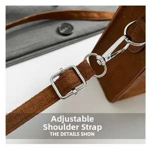 Detail of adjustable shoulder strap with silver metal buckle and brown suede texture
