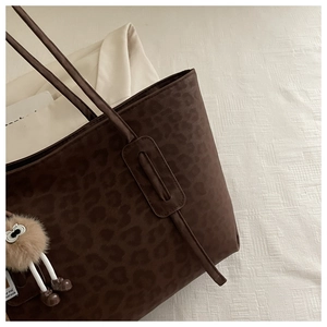 Close-up of leopard print tote bag with soft suede texture and cute plush doll pendant