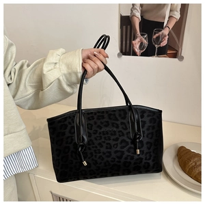 Detail of black leopard print tote bag with gold hardware and embossed logo branding