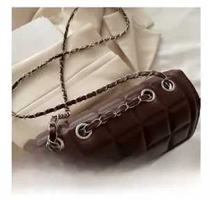 Detail of dark brown quilted leather bag with elegant chain strap and metal eyelet accents