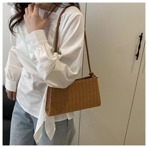 Detail view of woven baguette shoulder bag in caramel brown with knotted strap detail
