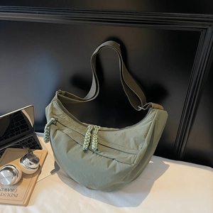 Grass green nylon half-moon crossbody bag with woven knot zipper and adjustable strap