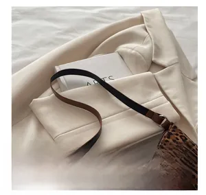 Detail of leopard print dumpling bag with dual-tone strap on cream suit background
