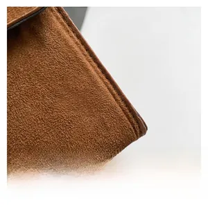Macro shot of brown suede texture and stitching detail on the women's crossbody bag