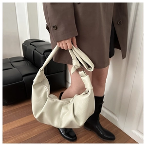 Close-up of off-white dumpling bag in lychee pattern leather with metal ring buckle details