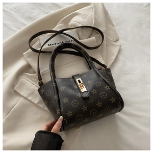 Close-up of monogram pattern tote bag with gold hardware and adjustable strap detail